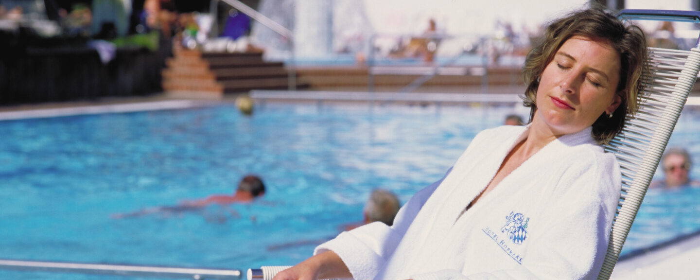 Eine Frau entspannt auf einer Liege neben einem Pool in Bad Griesbach