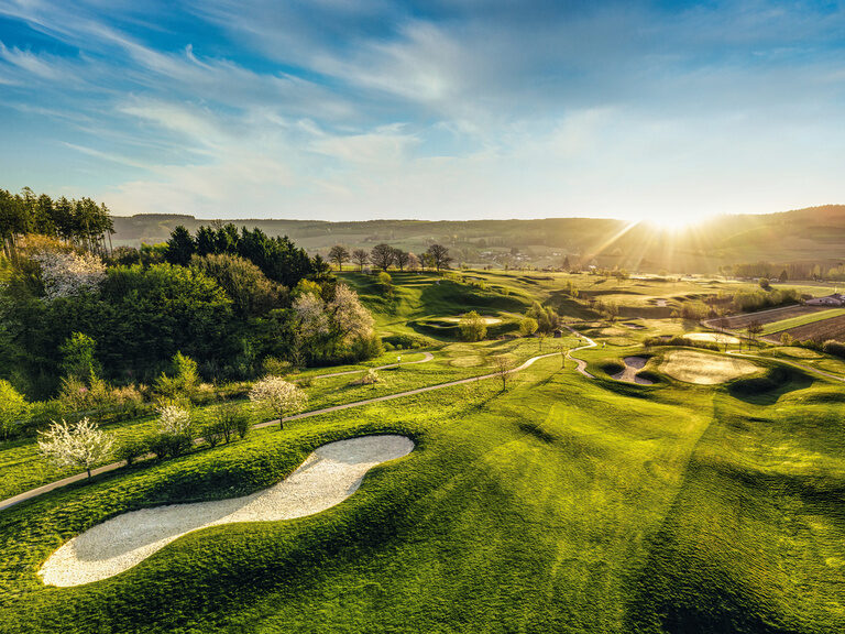 Über einem Golfplatz in Bad Birnbach geht die Sonne auf.