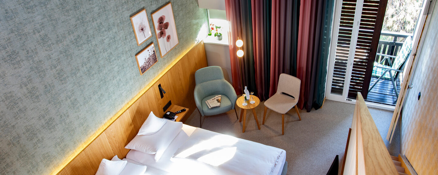 Der Blick von der Galerie des Galeriezimmers Komfort Deluxe auf das darunter liegende Bett mit im Thermenhotel Hofmark in Bad Birnbach