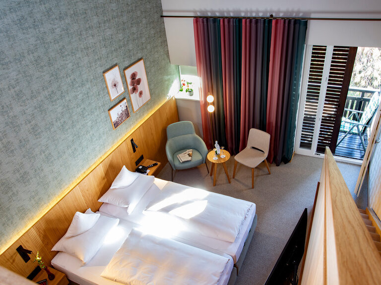 Der Blick von der Galerie des Galeriezimmers Komfort Deluxe auf das darunter liegende Bett mit im Thermenhotel Hofmark in Bad Birnbach