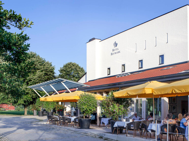 Der Biergarten des Hotels Hofmark vor dessen weißer Fassade bietet bei schönem Wetter einen super Ort zum Mittagessen.