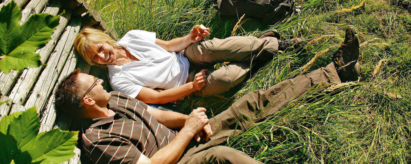 Ein Mann und eine Frau rasten an einer hölzernen Wand