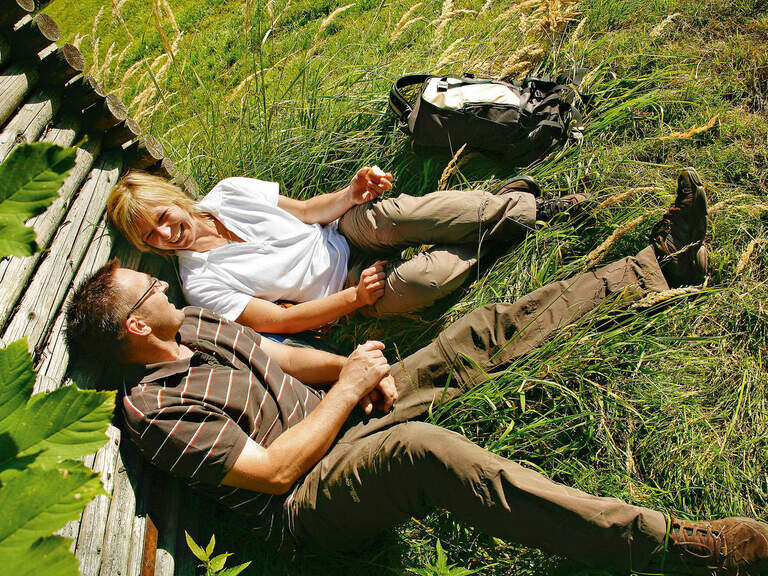 Ein Mann und eine Frau rasten an einer hölzernen Wand