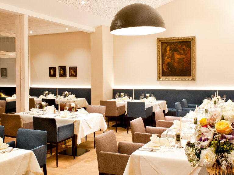 Das Bild zeigt das schön dekorierte Restaurant im Hotel Hofmark mit gedeckten Tischen und Blumenschmuck